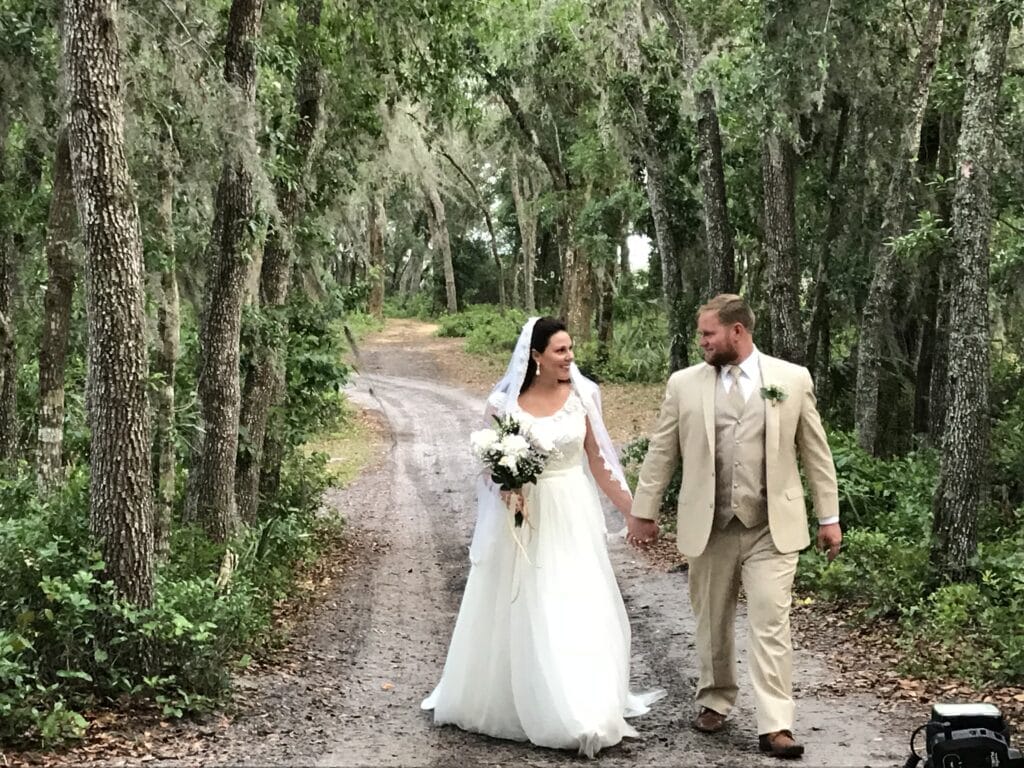 bride and groom holding hands and walking down path in the woods